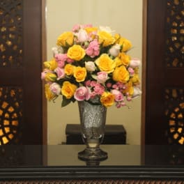 Yellow and pink roses arranged in a clear glass vase