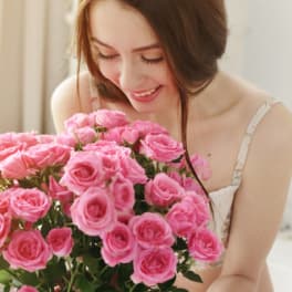 Woman holding a large bouquet of pink roses