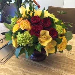 Mixed bouquet of red and yellow roses in a dark vase