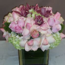 Pink roses and calla lilies arranged in a square glass vase