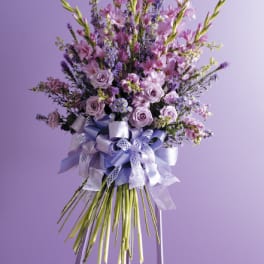 Tall lavender floral spray on an easel with a large ribbon bow