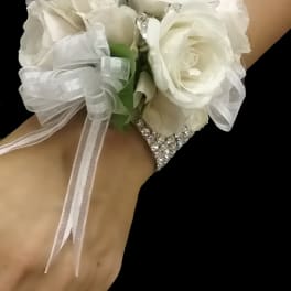 White rose wrist corsage with sheer ribbon on a rhinestone bracelet band.