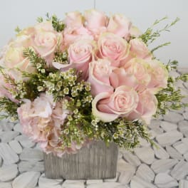 Pink roses and pale hydrangea in a square wooden vase