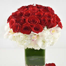 Red roses and white orchids in a square glass vase