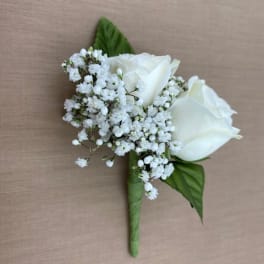 White rose boutonniere with baby's breath and green leaves