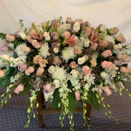 Large pastel floral spray with roses, lilies, and white blooms on a stand