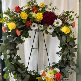 Large floral wreath with roses and daisies on a black stand