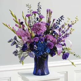 Purple and blue floral arrangement in a cobalt vase