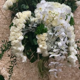 White floral arrangement in a clear vase with roses and orchids