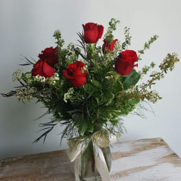 Bouquet of red roses in a glass vase with white ribbon