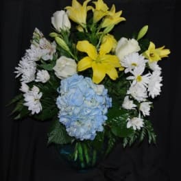 Yellow lilies and white daisies with a blue hydrangea in a vase