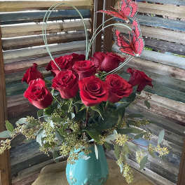 Red roses in a turquoise vase with butterfly picks