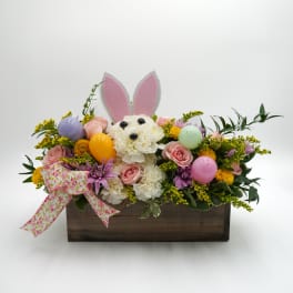Floral arrangement in a wooden box with a bunny face and ears
