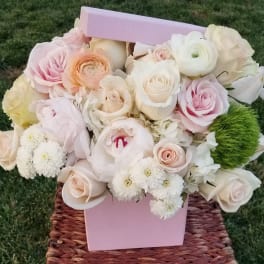 Pastel bouquet of roses and ranunculus in a pink box
