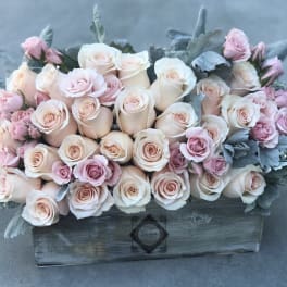Arrangement of pale pink and cream roses in a wooden box