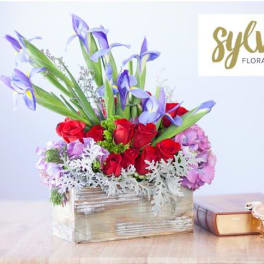 Red roses and purple irises in a rustic wooden box