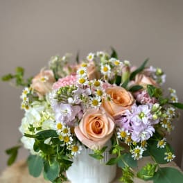 Peach roses and pastel flowers arranged in a white vase