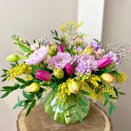Mixed bouquet of pink and lavender flowers in a glass vase