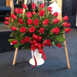 Large bouquet of red roses in a white vase with a red ribbon