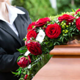 Red rose casket spray on a wooden coffin