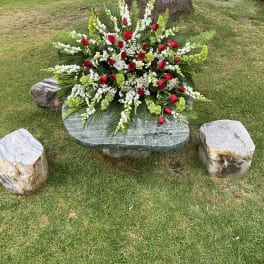 Large red and white floral arrangement on a stone bench outdoors