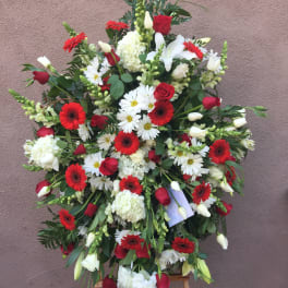 Large standing spray of red, white, and green flowers on an easel