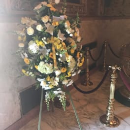Large funeral spray of white and yellow flowers on an easel