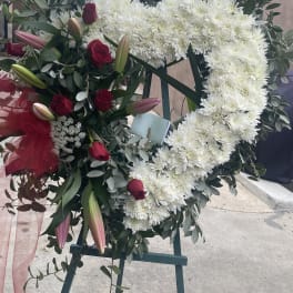 Heart-shaped floral wreath with white chrysanthemums and red roses on an easel