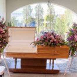 Casket surrounded by large pink and purple floral sprays