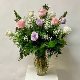 Bouquet of pink, white, and lavender roses in a clear glass vase