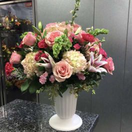 Large pink and white floral arrangement in a white vase