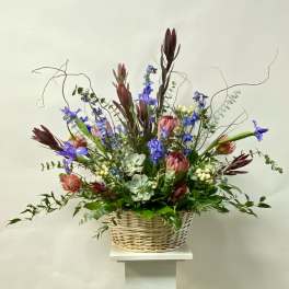 Tall mixed flower arrangement in a wicker basket