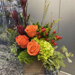 Orange roses and green hydrangea in a wooden box with berries