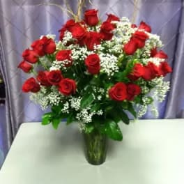 Red roses arranged in a clear glass vase with white filler flowers