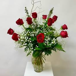 Red roses arranged in a clear glass vase with white baby's breath