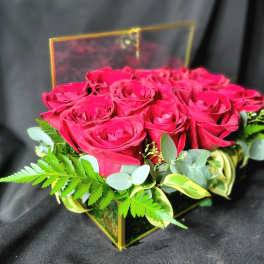 Box arrangement of red roses in a clear square container with the lid propped open