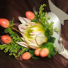 Cream and green protea boutonniere with pink berries wrapped in ivory ribbon and pearl pin