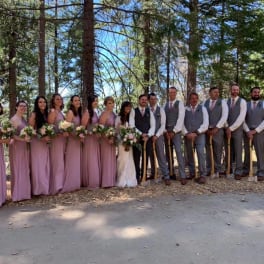 Wedding party in mauve dresses and gray suits holding bouquets outdoors