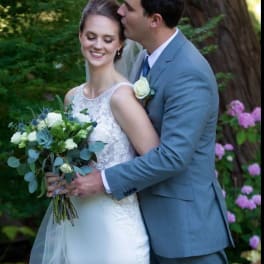 Bride holding a white and blue bouquet beside a groom in a gray suit