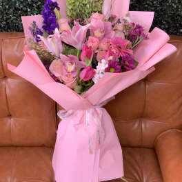 Pink bouquet with lilies, roses, and purple flowers wrapped in pink paper