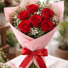Bouquet of red roses wrapped in pink paper with a red ribbon