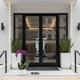 Orchid arrangement in white planters at a modern building entrance