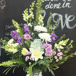 Large mixed floral arrangement in a white pedestal vase