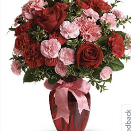 Red roses and pink carnations in a red vase with a pink ribbon