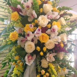 Large standing floral arrangement with yellow and white roses and orchids