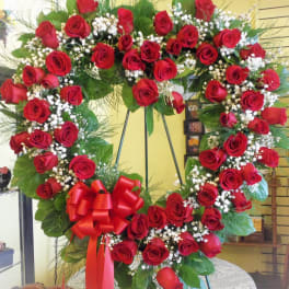 Heart-shaped wreath of red roses with a red bow on a stand