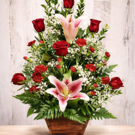 Red roses and pink lilies arranged in a wooden basket