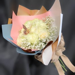 Bouquet of pale yellow roses with baby's breath in pastel wrapping
