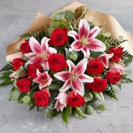 Bouquet of red roses and pink lilies wrapped in brown paper