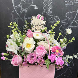 Pink and white flower arrangement in a pink gift bag with a Hello Kitty topper